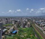 Stunning aerial shot of Mumbai's skyline, showcasing the bustling cityscape and vivid greenery under a clear blue sky.